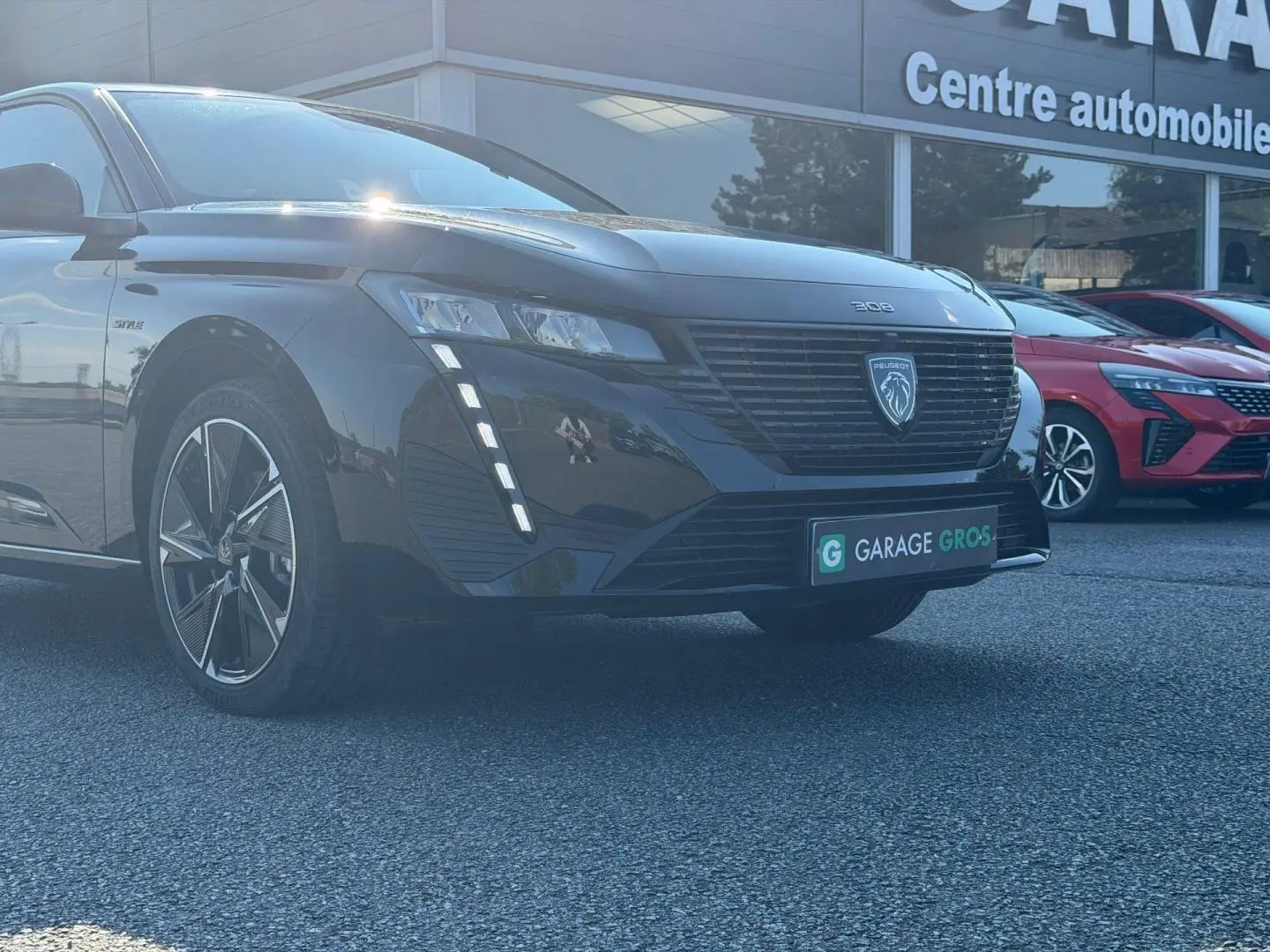 Peugeot e-308 noir Perla Nera vue 3/4 avant gauche, avec feux LED verticaux et jantes alu distinctives.