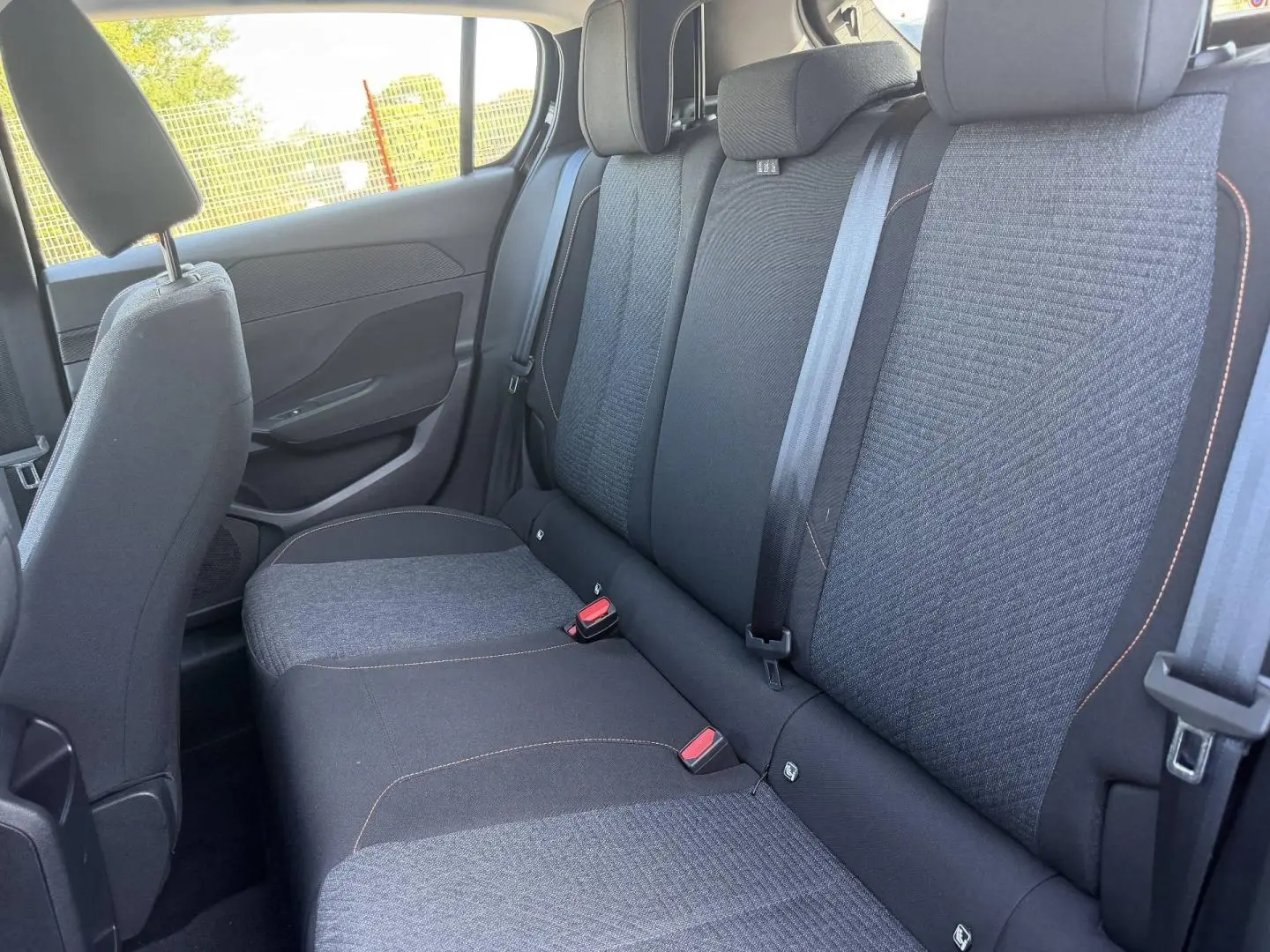 Vue latérale droite de la banquette arrière en tissu gris anthracite avec surpiqûres orange de la Peugeot 308 e-308 2025.