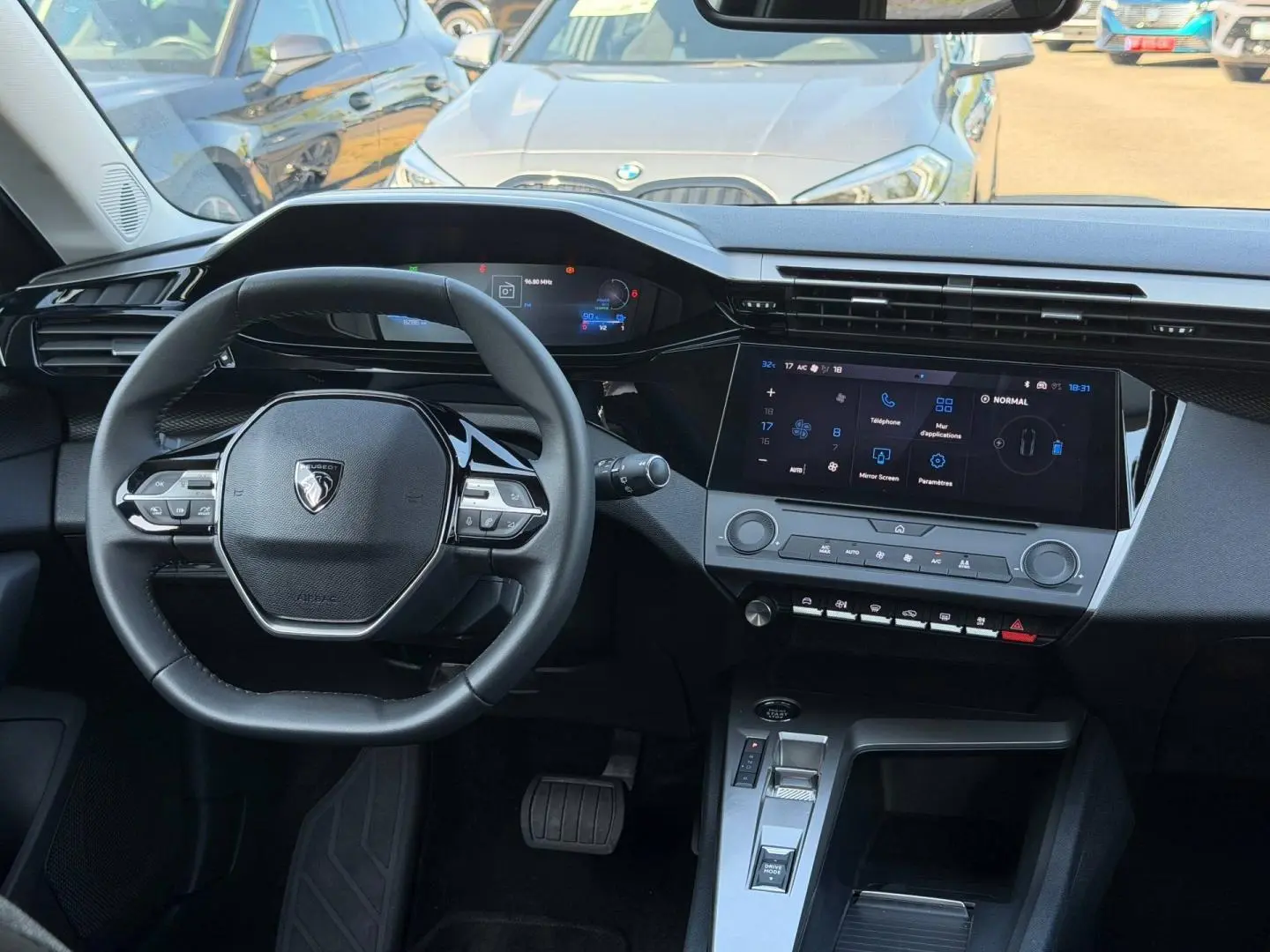 Vue intérieure avant du tableau de bord et volant noir de la Peugeot e-308 2025 avec écran tactile et commandes multifonctions.
