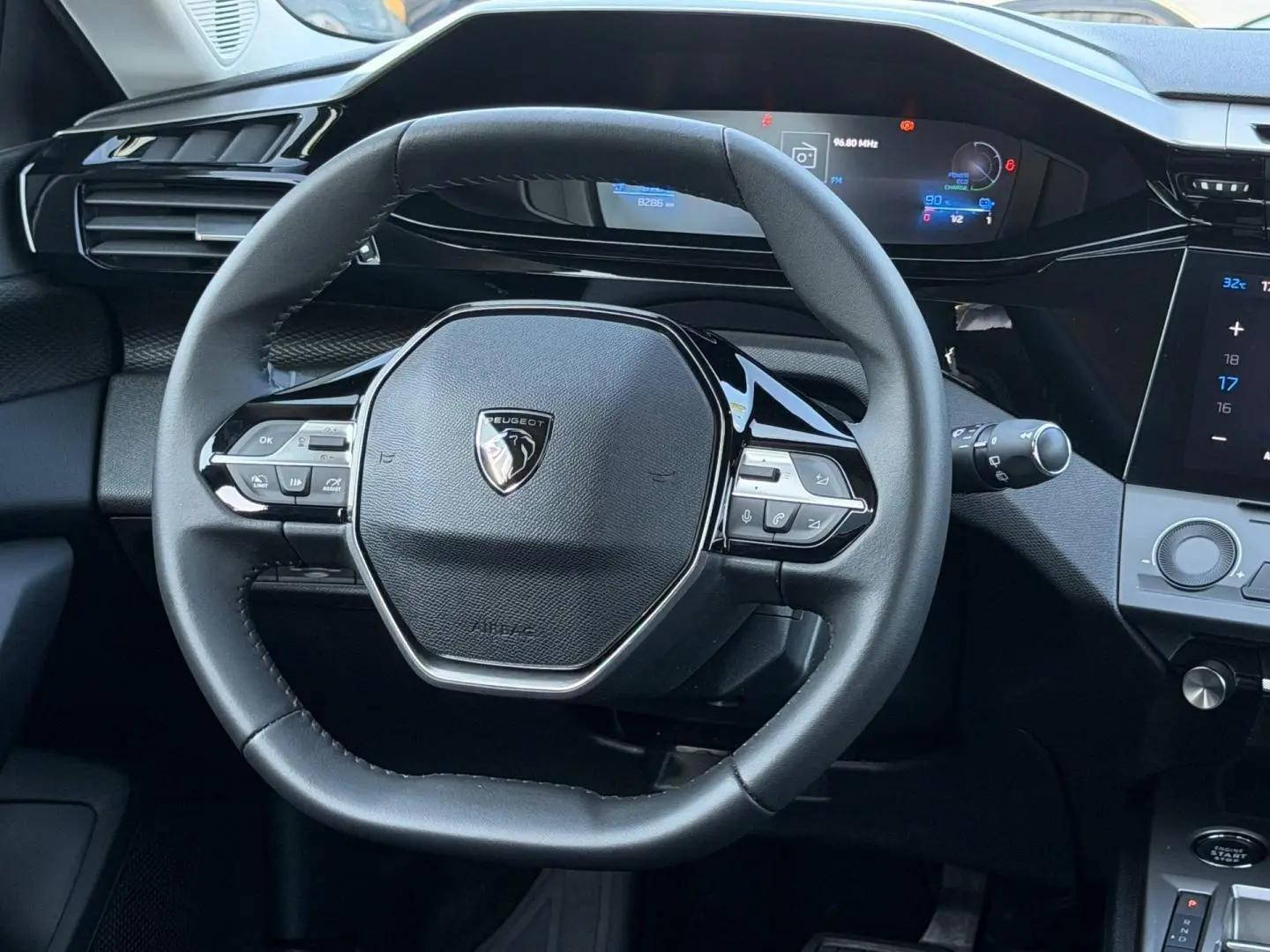 Vue rapprochée du volant multifonction noir et du tableau de bord numérique de la Peugeot e-308 2025.