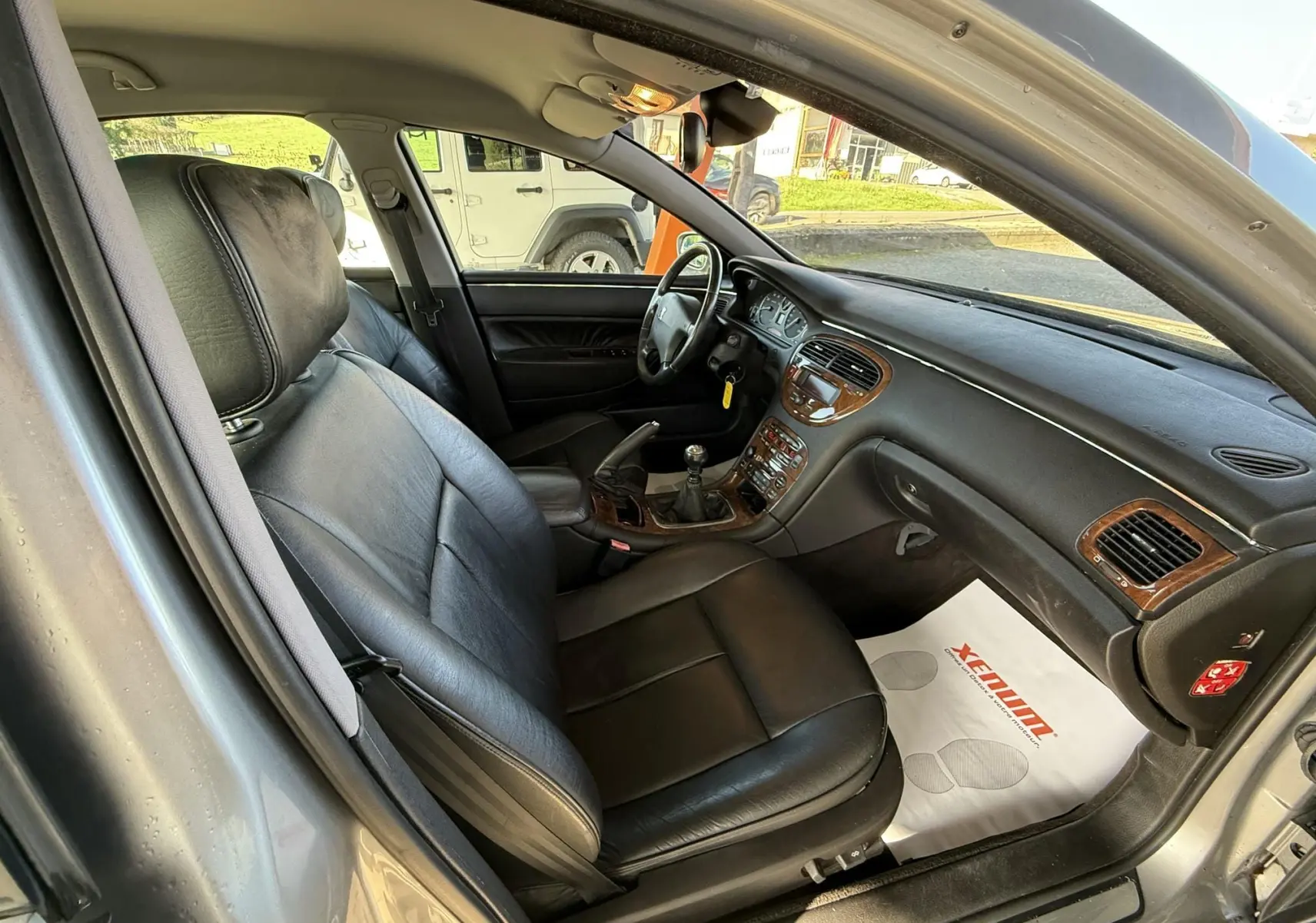 Intérieur cuir noir de la Peugeot 607 gris, vue côté conducteur avec tableau de bord et levier de vitesse manuel visible.