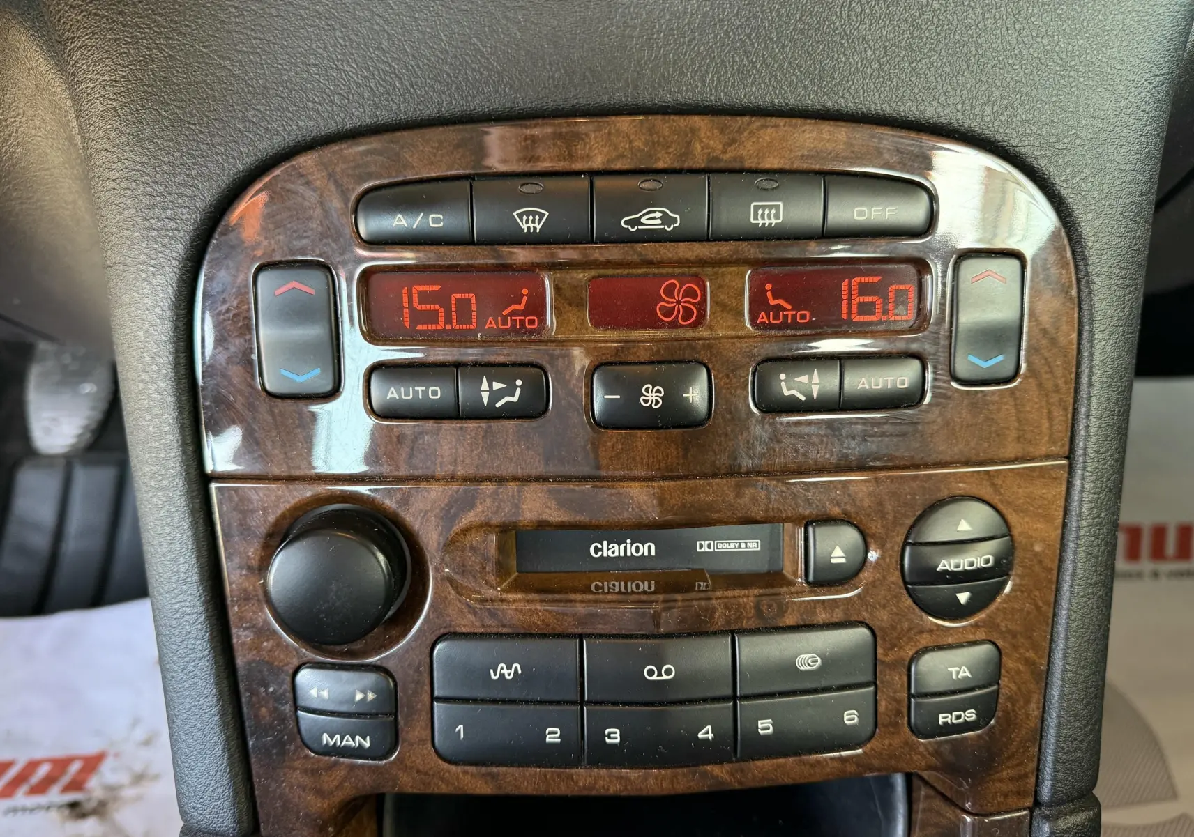 Tableau de bord en bois foncé de Peugeot 607 gris, avec commandes climatisation et autoradio Clarion visibles.