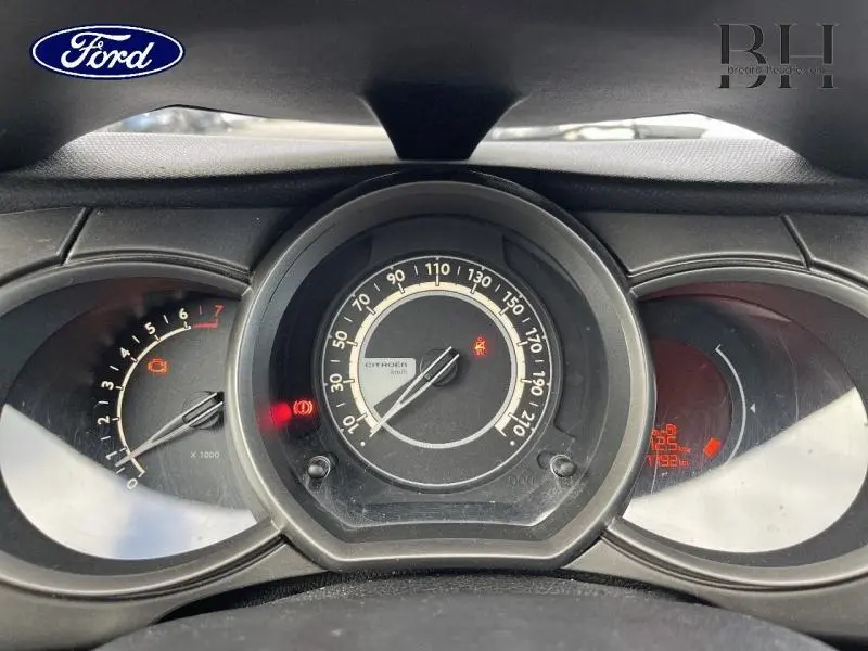 Vue rapprochée du tableau de bord de la Citroën C3 bleu encre, avec compteur central et voyants allumés.