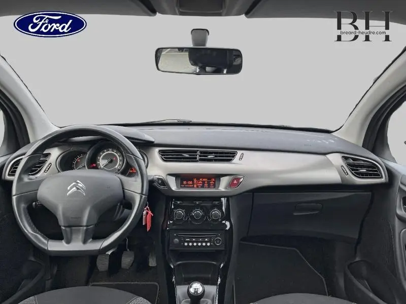 Vue intérieure avant du tableau de bord et volant Citroën C3 bleu encre avec commandes et levier de vitesse manuel visibles.