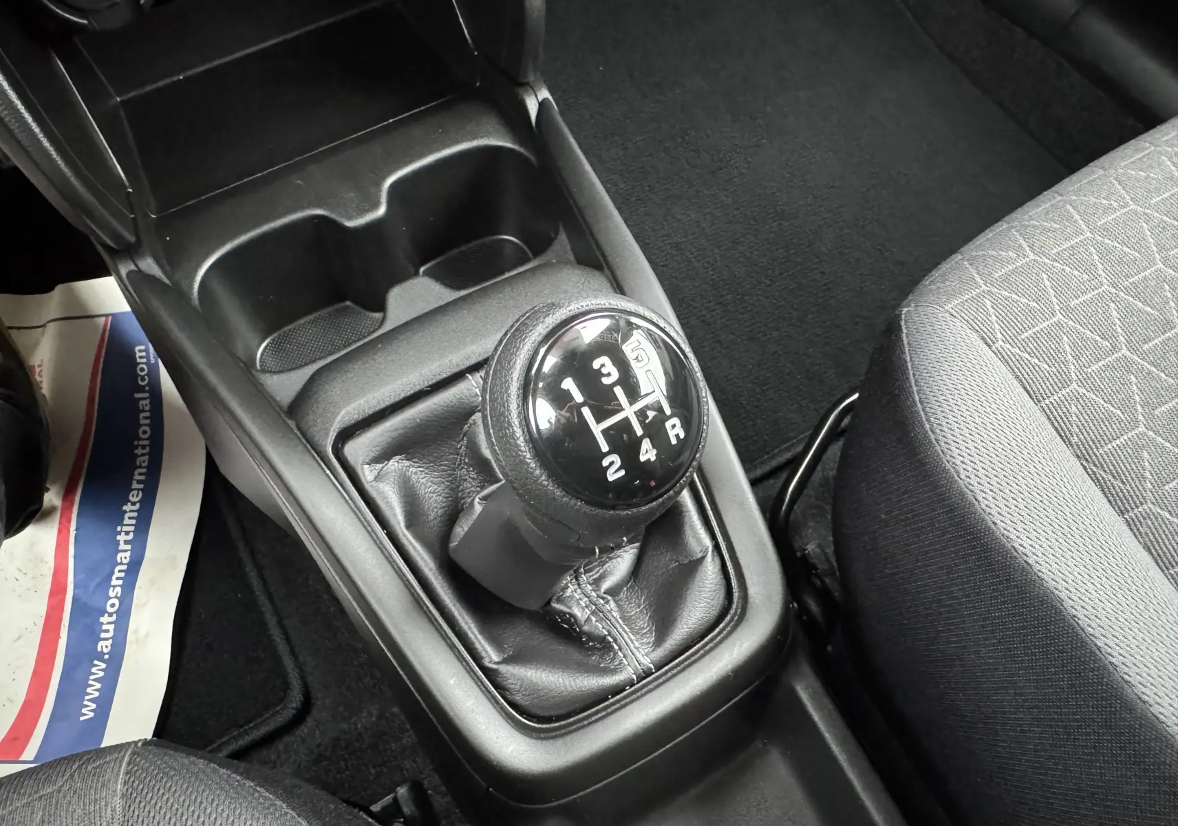 Gros plan sur le levier de vitesses manuel noir de la Suzuki Swift 1.2 Privilège Hybrid 2025, intérieur gris.