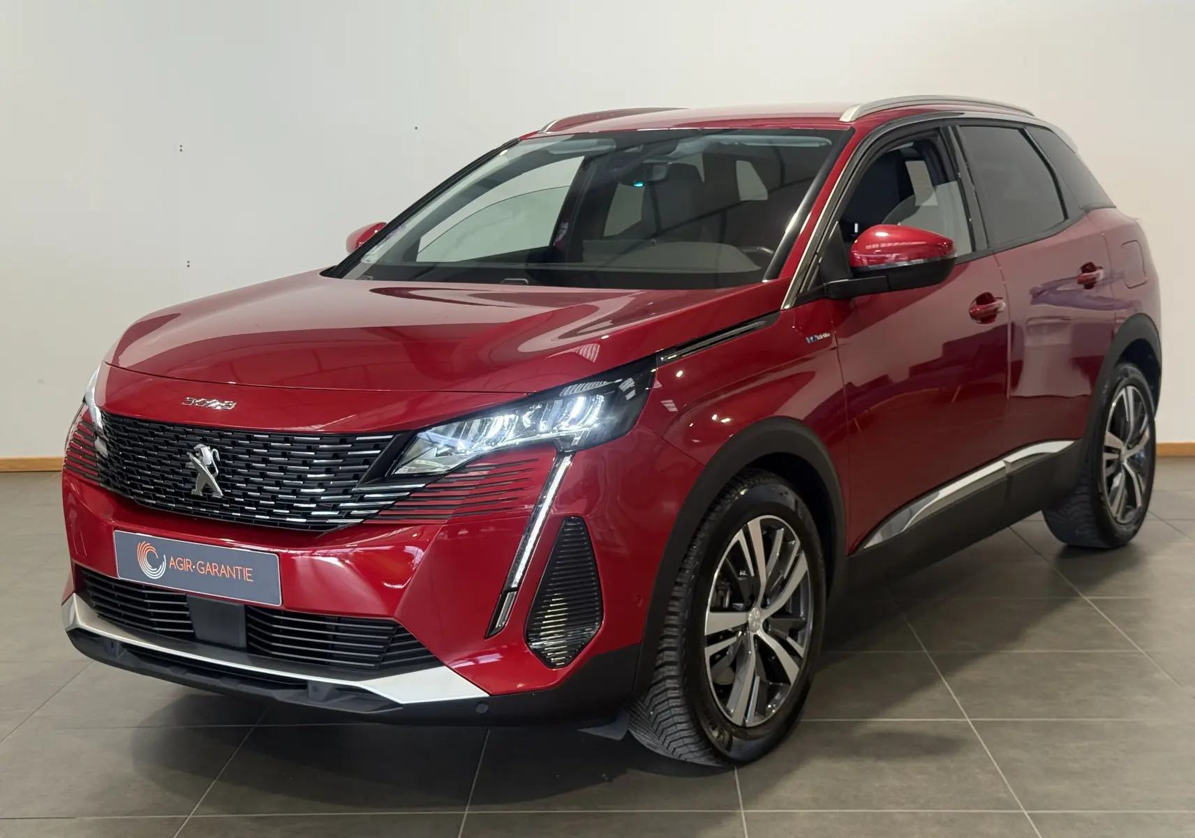 Peugeot 3008 Hybrid rouge 2025 en 3/4 avant droit, avec calandre noire et feux LED allumés.