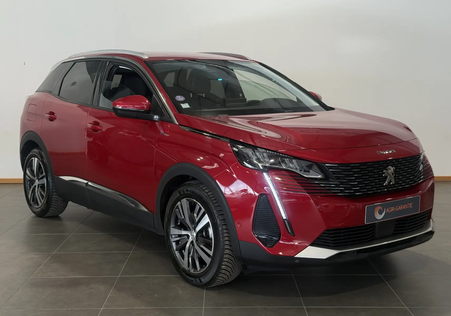 Peugeot 3008 Hybrid rouge 2025 en 3/4 avant droit, avec feux LED verticaux et jantes alliage distinctives.