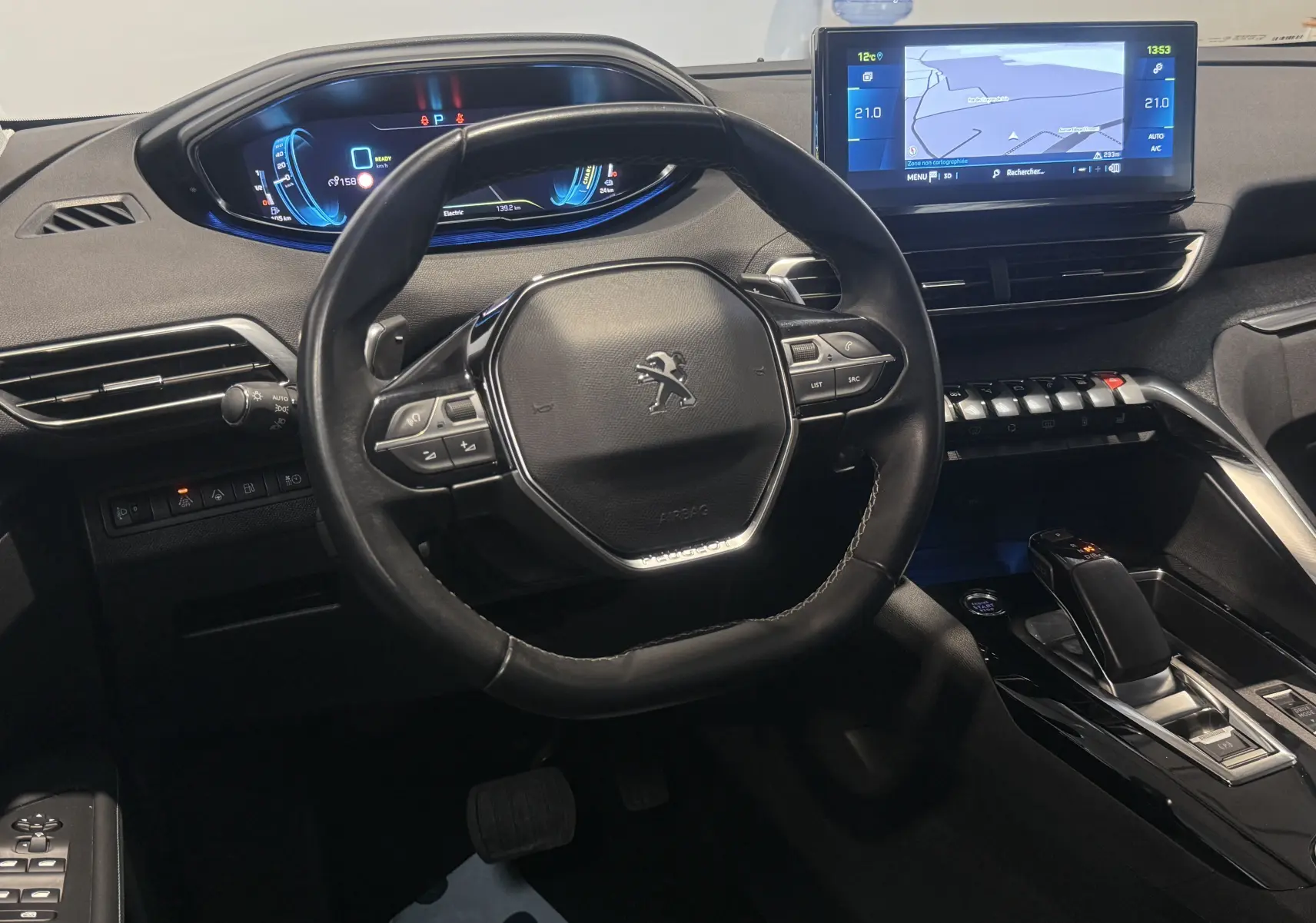 Vue intérieure centrée sur le volant et le tableau de bord numérique du Peugeot 3008 Hybrid rouge 2025.