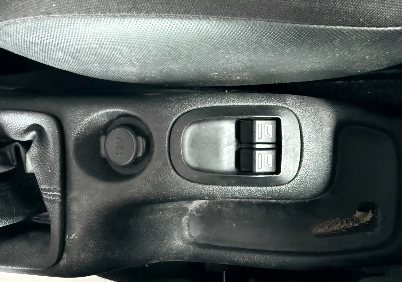 Gros plan sur le levier de vitesses manuel et la console centrale noire du Peugeot 206+ bleu, siège tissu visible à droite.