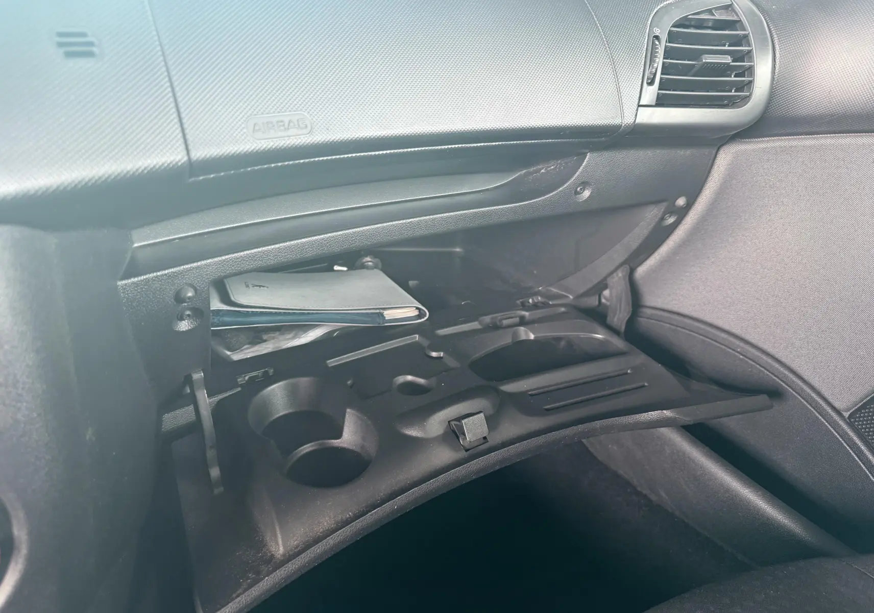 Vue rapprochée de la console centrale noire entre les sièges avant d’une Peugeot 206+ 2011.