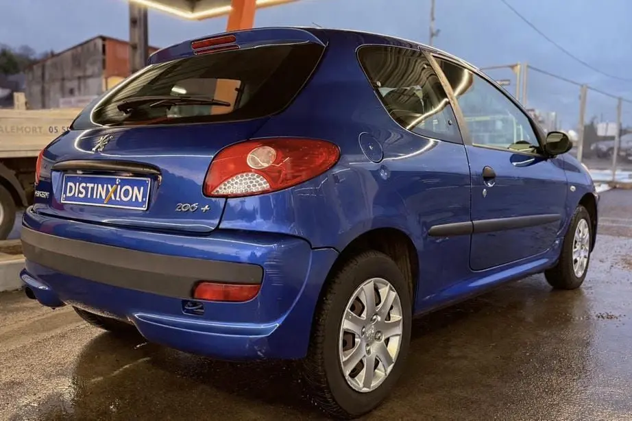 Vue arrière d'une Peugeot 206+ bleue avec feux allumés et plaque d'immatriculation Distinxion.