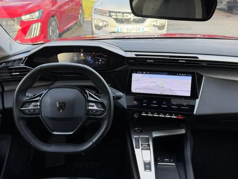 Vue intérieure du poste de conduite de la Peugeot 308 2024, avec volant compact et écran tactile central allumé.