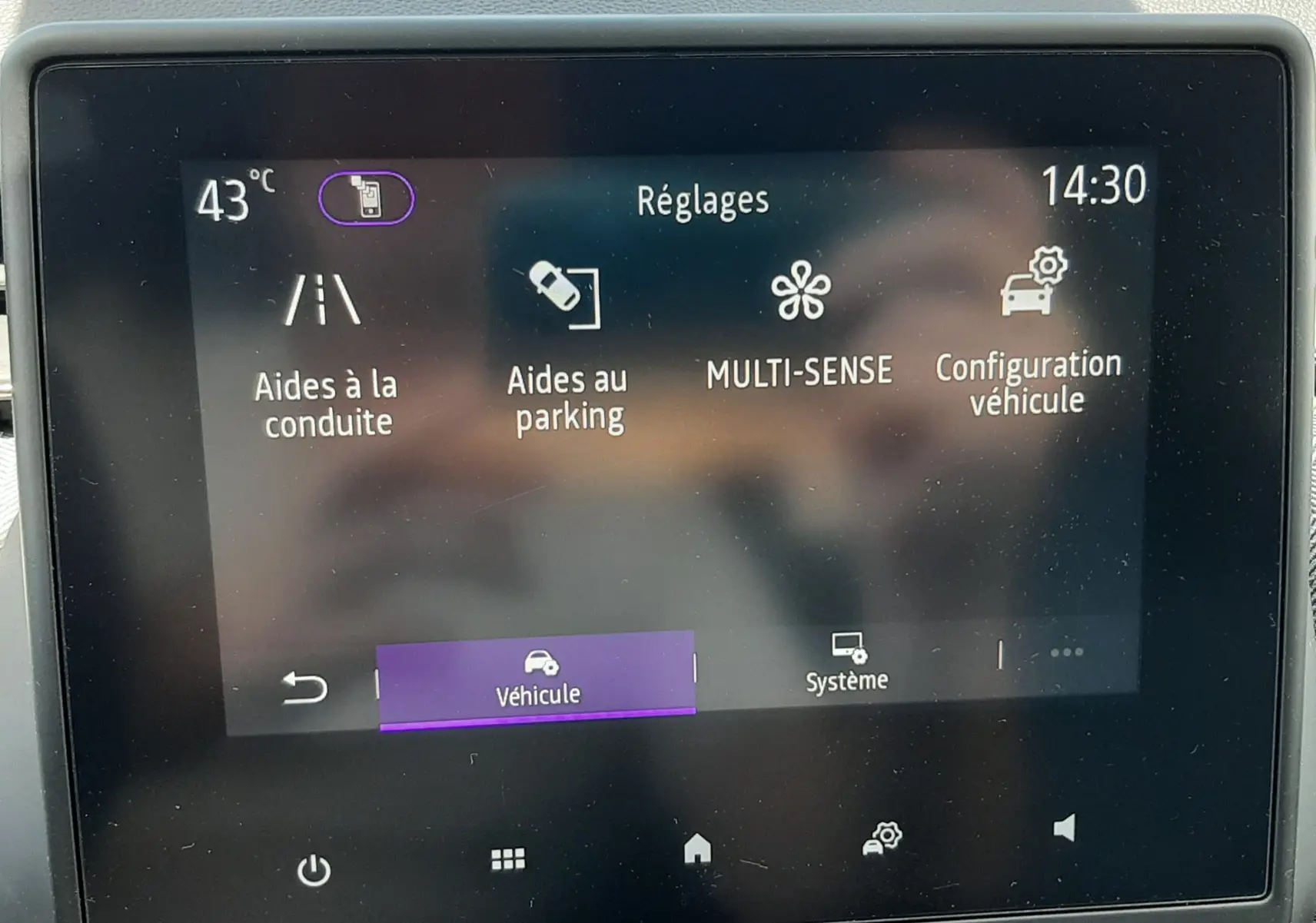 Écran tactile central de la Renault Clio V rouge flamme, affichant le menu Réglages avec options d'aides à la conduite et parking.