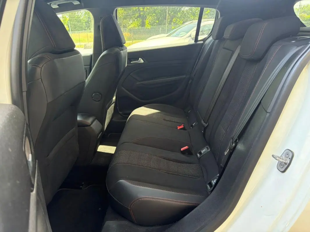 Vue intérieure arrière côté droit du Peugeot 308 GT-Line blanc, montrant les sièges arrière en tissu noir avec surpiqûres rouges.