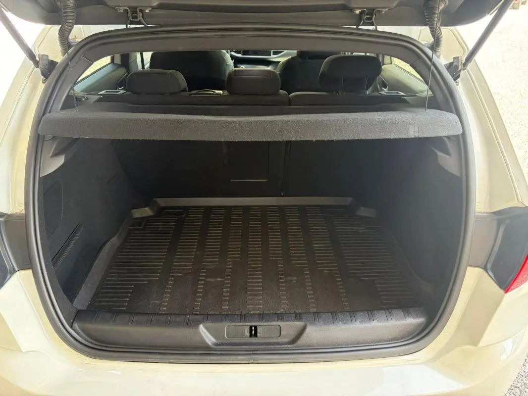 Coffre ouvert d'une Peugeot 308 GT-Line blanche de 2017, vue arrière montrant l'espace de chargement et la tablette cache-bagages.