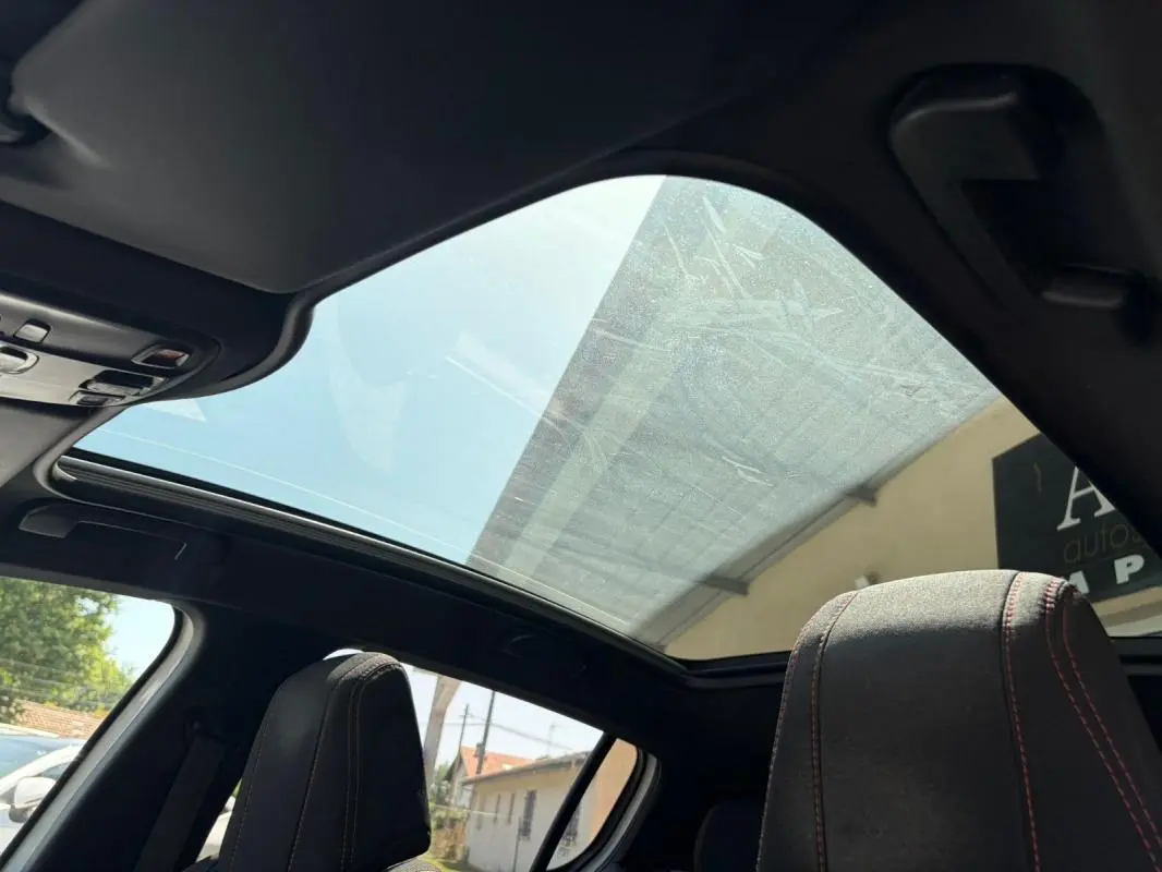 Toit panoramique en verre vu de l'intérieur sur Peugeot 308 GT-Line 2017 avec sièges noirs et surpiqûres rouges.