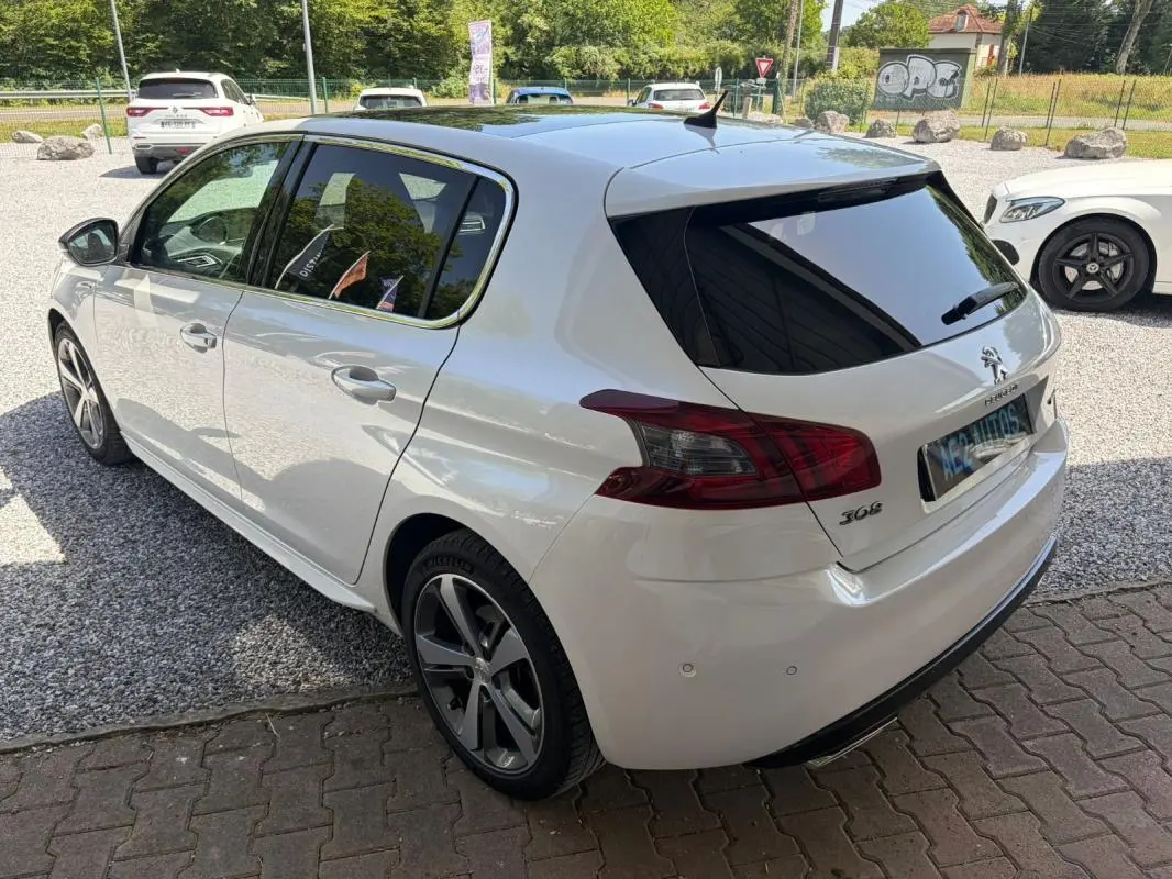 Peugeot 308 GT-Line blanc vue 3/4 arrière droit, avec jantes alliage et vitres arrière teintées.