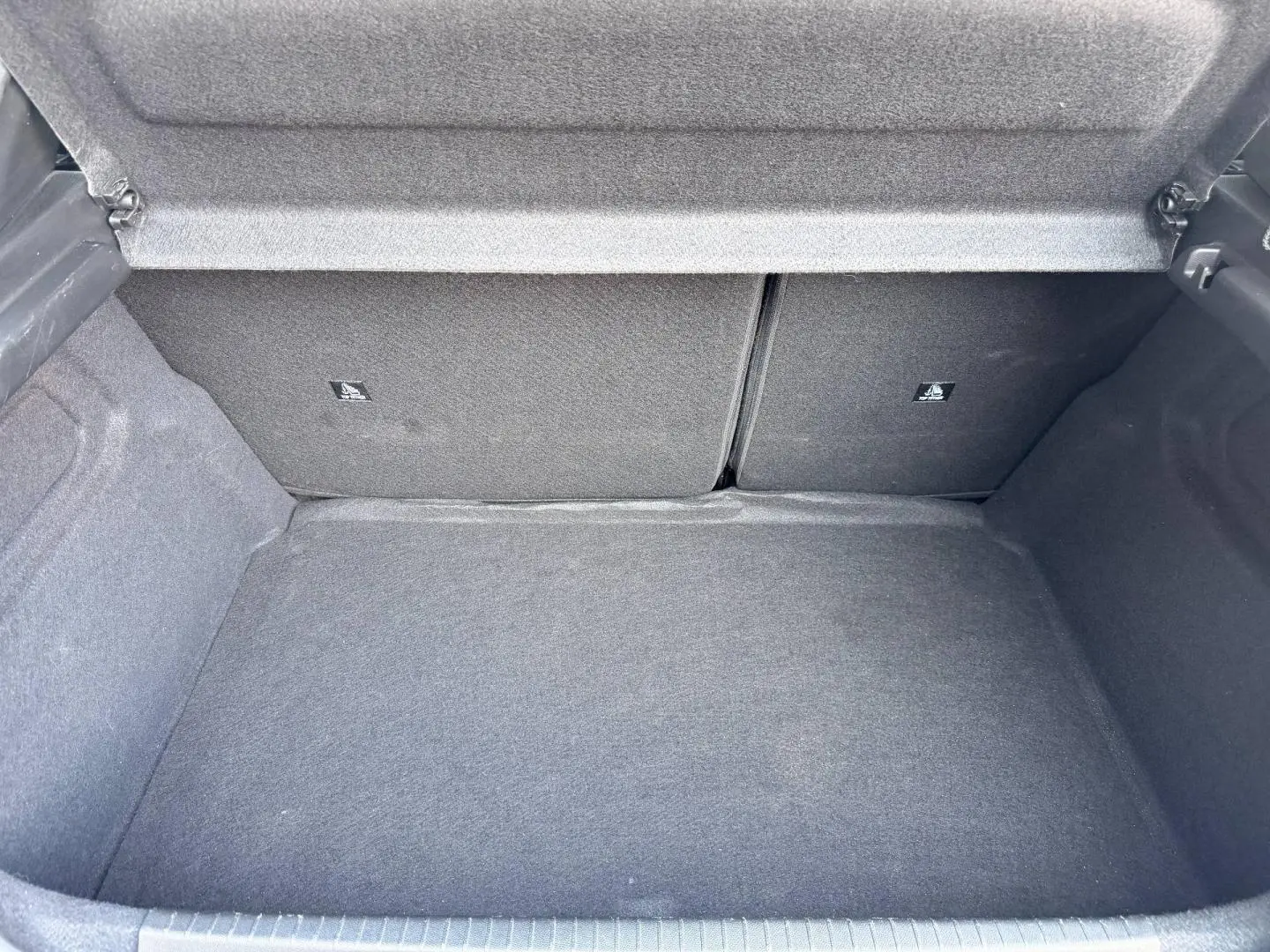 Coffre ouvert de la Peugeot 208 1.2 100ch gris Artense, vue intérieure montrant la banquette arrière rabattable.