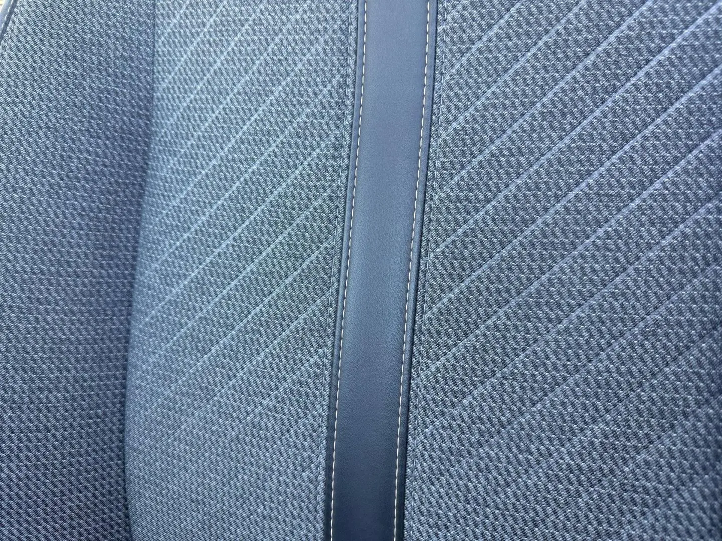 Détail du tissu gris Casual Lomsa avec surpiqûres et bande centrale en simili cuir sur siège Peugeot 208 2025.