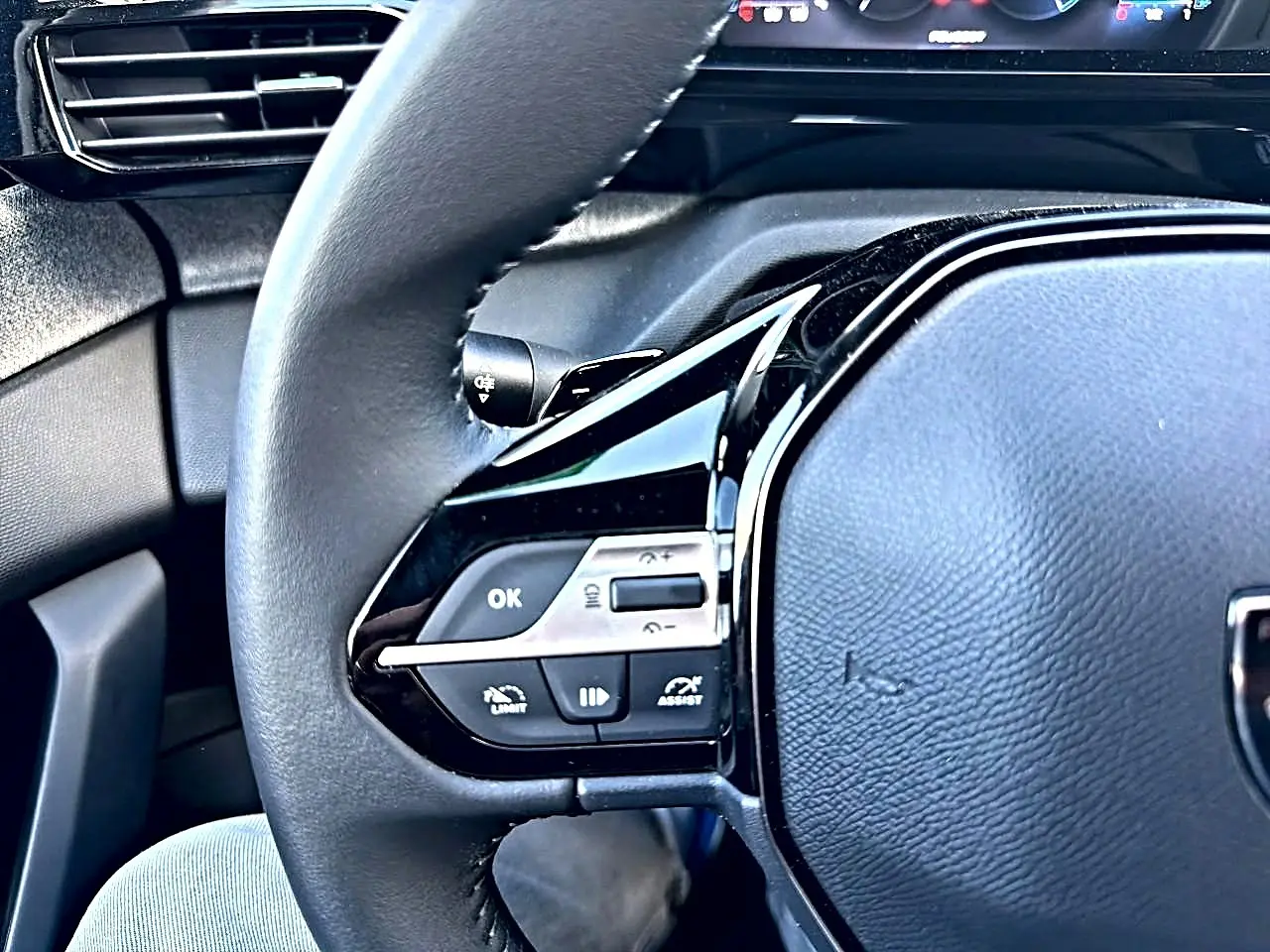 Gros plan sur le volant multifonction noir de la Peugeot 308 1.5 BlueHDi 130 Allure, avec commandes intégrées.
