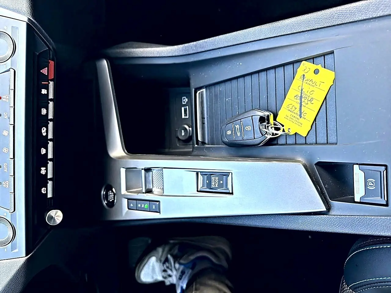 Vue plongeante sur la console centrale grise de la Peugeot 308 2025 avec clé et bouton Drive Mode visible.