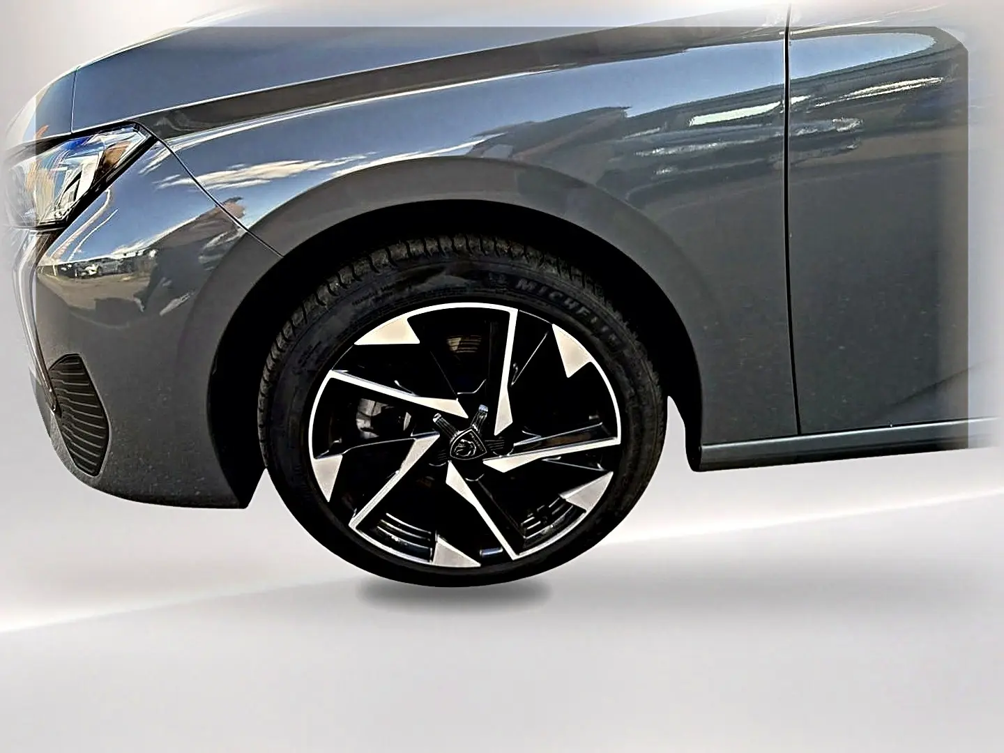 Gros plan sur la roue avant gauche et l'aile d'une Peugeot 308 gris selenium avec jante alu noire et argentée.