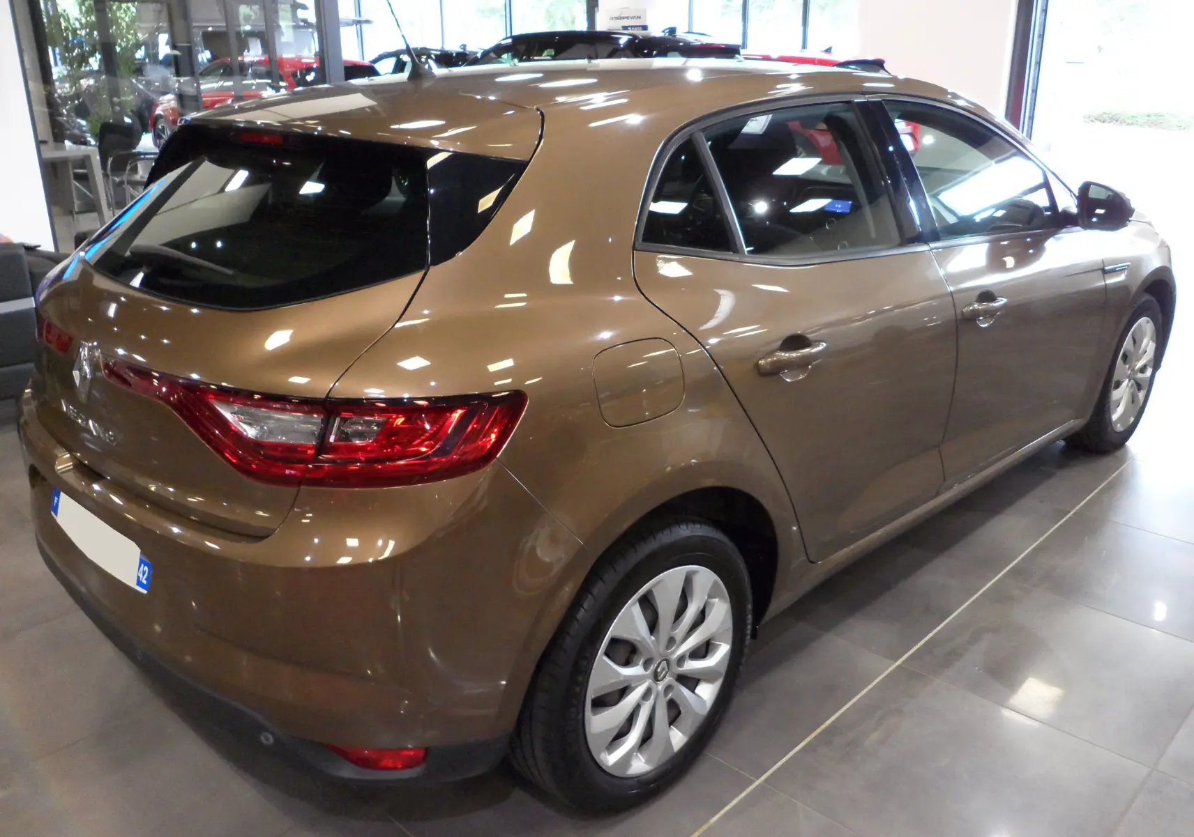 Renault Mégane IV TCe 100 Life brun capuccino vue 3/4 arrière droit avec feux arrière allumés et plaque occasion.