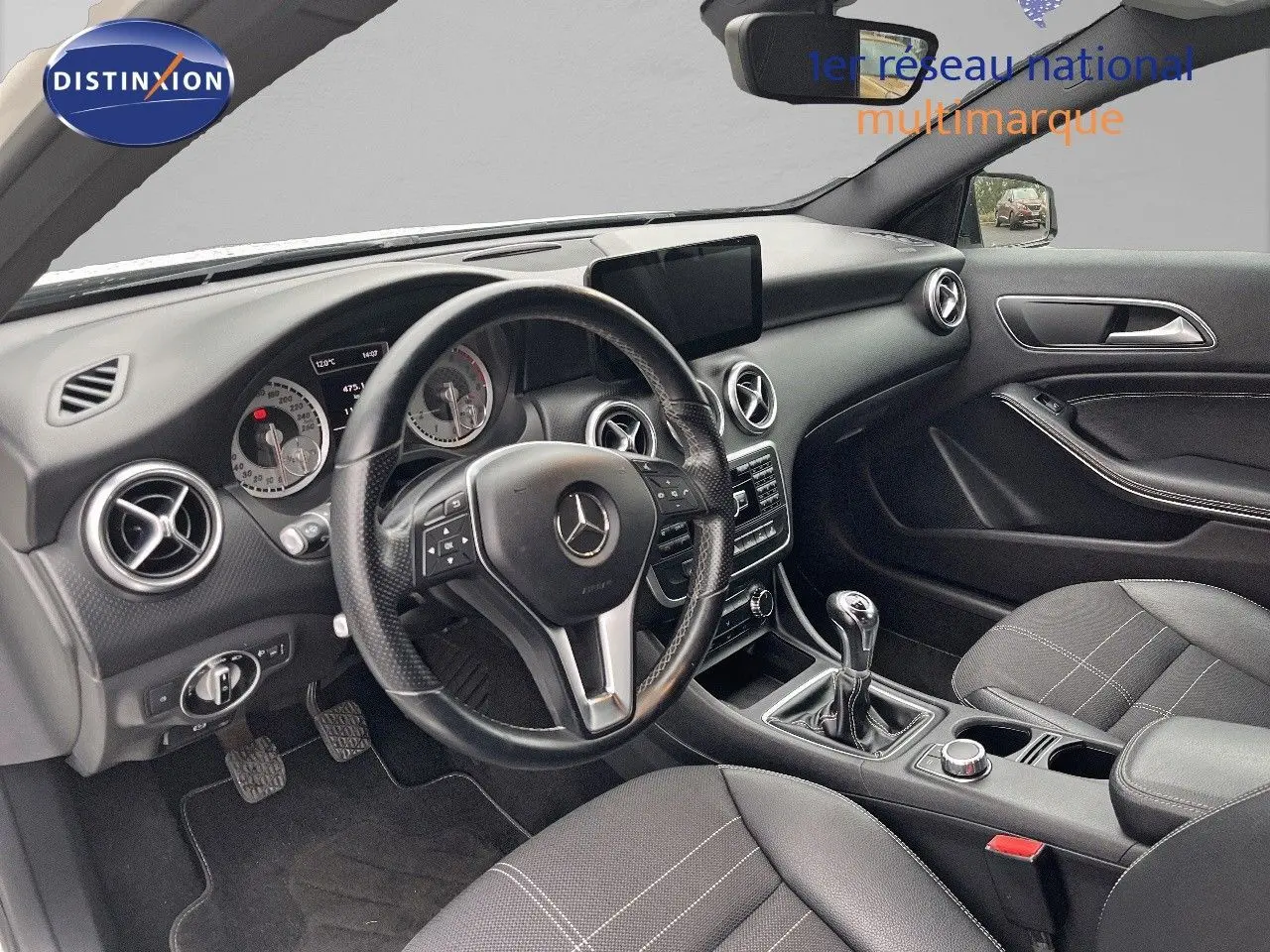Vue intérieure côté conducteur d'une Mercedes Classe A 180 Sensation 2013 avec volant cuir et boîte manuelle.