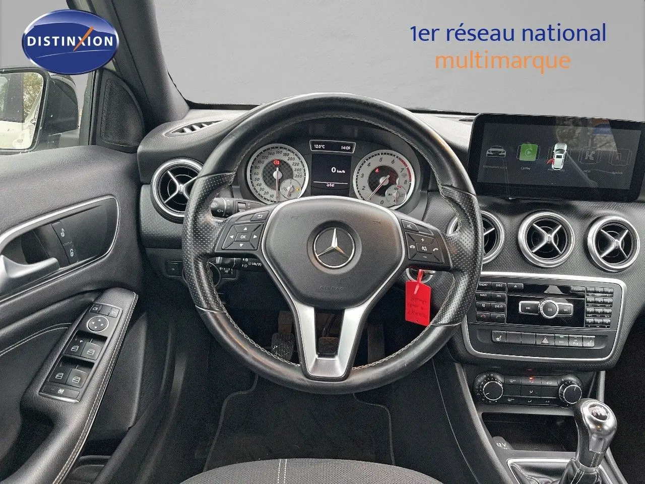 Vue intérieure du poste de conduite d'une Mercedes Classe A 180 Sensation blanche de 2013 avec volant multifonction et boîte manuelle.