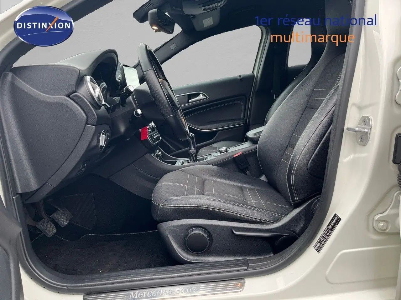 Intérieur côté conducteur d'une Mercedes Classe A 180 Sensation blanche de 2013, avec sièges noirs et boîte manuelle.