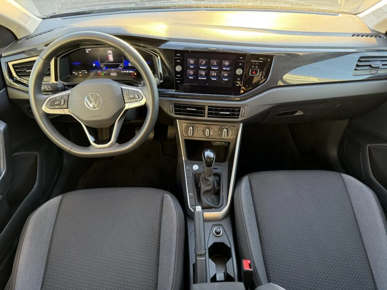 Vue intérieure avant du Volkswagen Taigo 2025, tableau de bord noir avec écran tactile et volant multifonction.