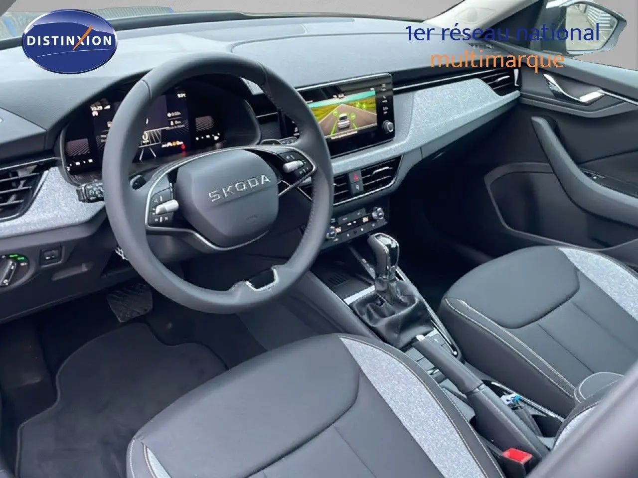Vue intérieure côté conducteur du Skoda Kamiq 2025 avec tableau de bord moderne et sellerie tissu gris et noir.