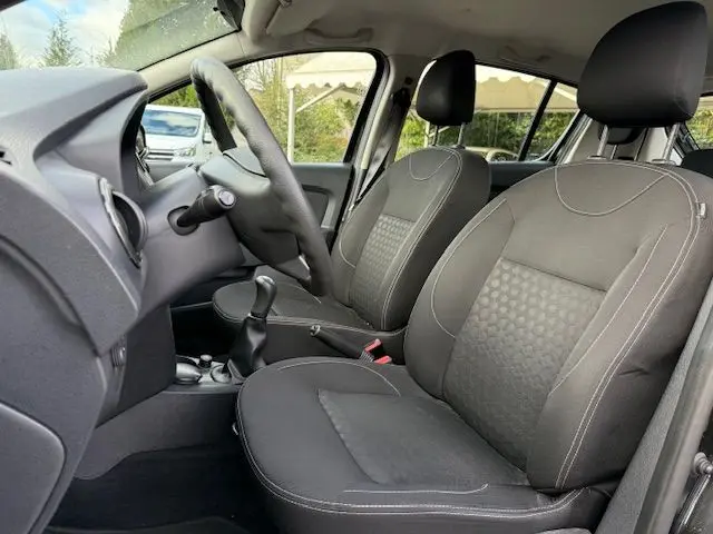 Vue intérieure côté conducteur de la Dacia Sandero noire 2015, montrant les sièges en sellerie Lauréate et la boîte manuelle.