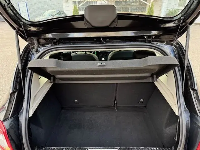 Vue arrière du coffre ouvert d'une Dacia Sandero noire 2015, montrant l'espace de chargement et la banquette arrière.