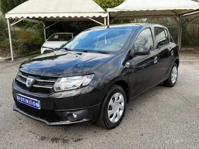 Dacia Sandero noire vue en 3/4 avant droit, avec calandre chromée et jantes acier à enjoliveurs.