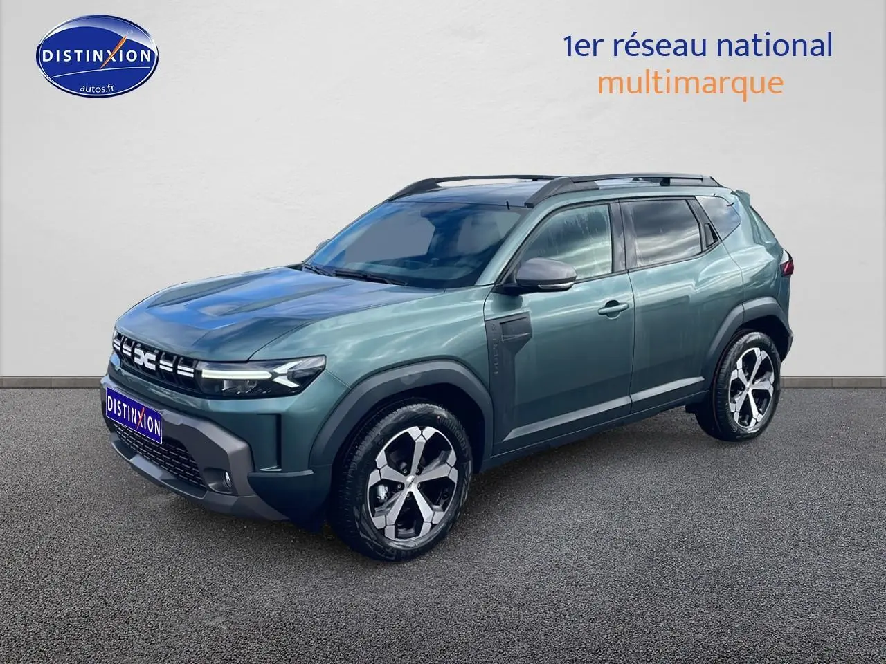 Dacia Duster 1.2 mild hybrid vert cèdre en 3/4 avant droit, avec jantes alu et barres de toit noires.