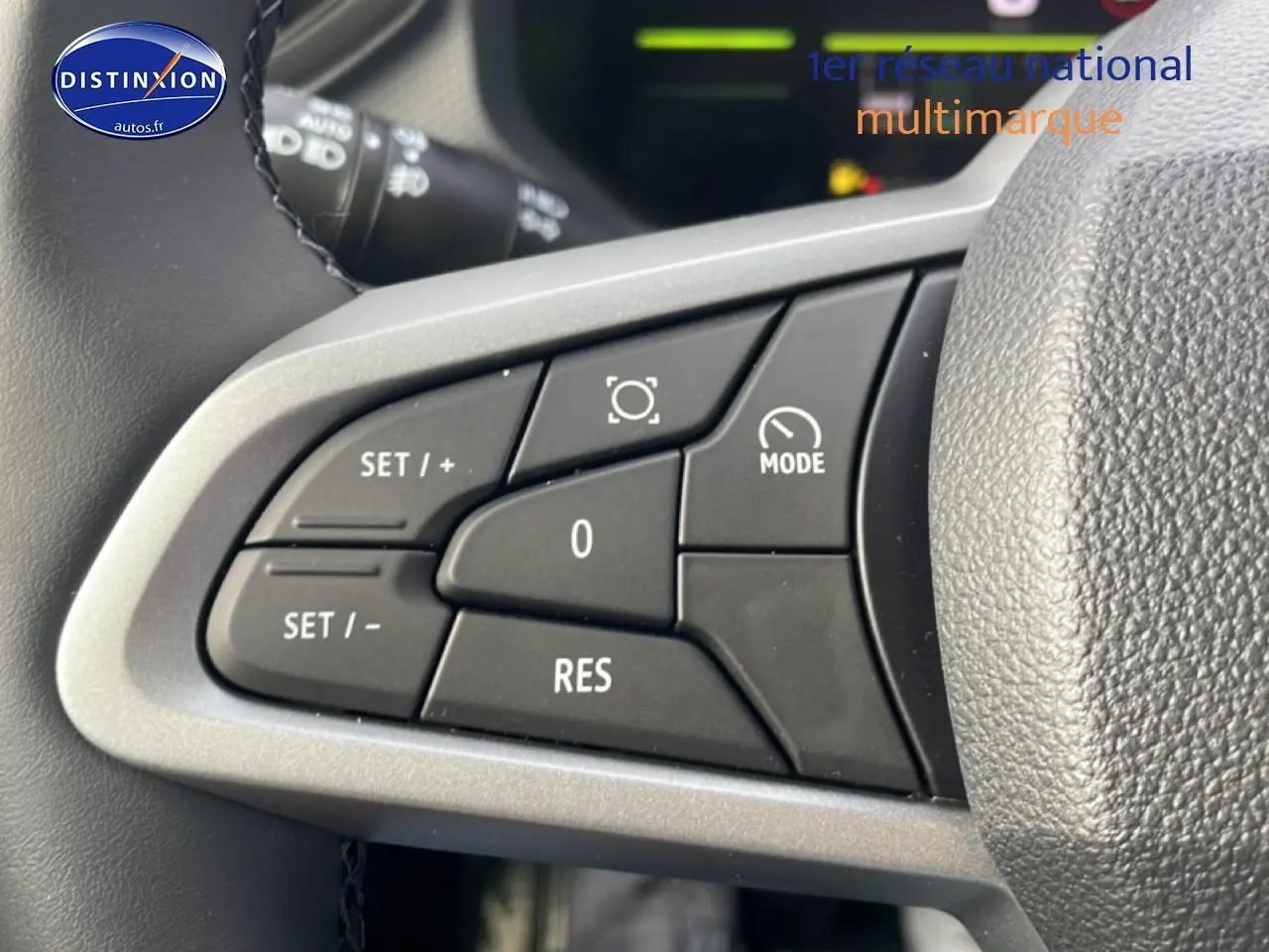 Gros plan sur les commandes multifonctions noires du volant côté gauche du Dacia Duster 2026 vert cèdre.