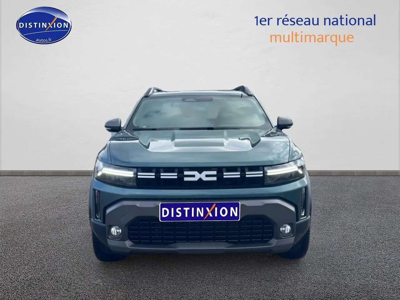 Vue frontale d’un Dacia Duster 1.2 mild hybrid 140 Journey vert cèdre avec calandre noire et feux LED allumés.