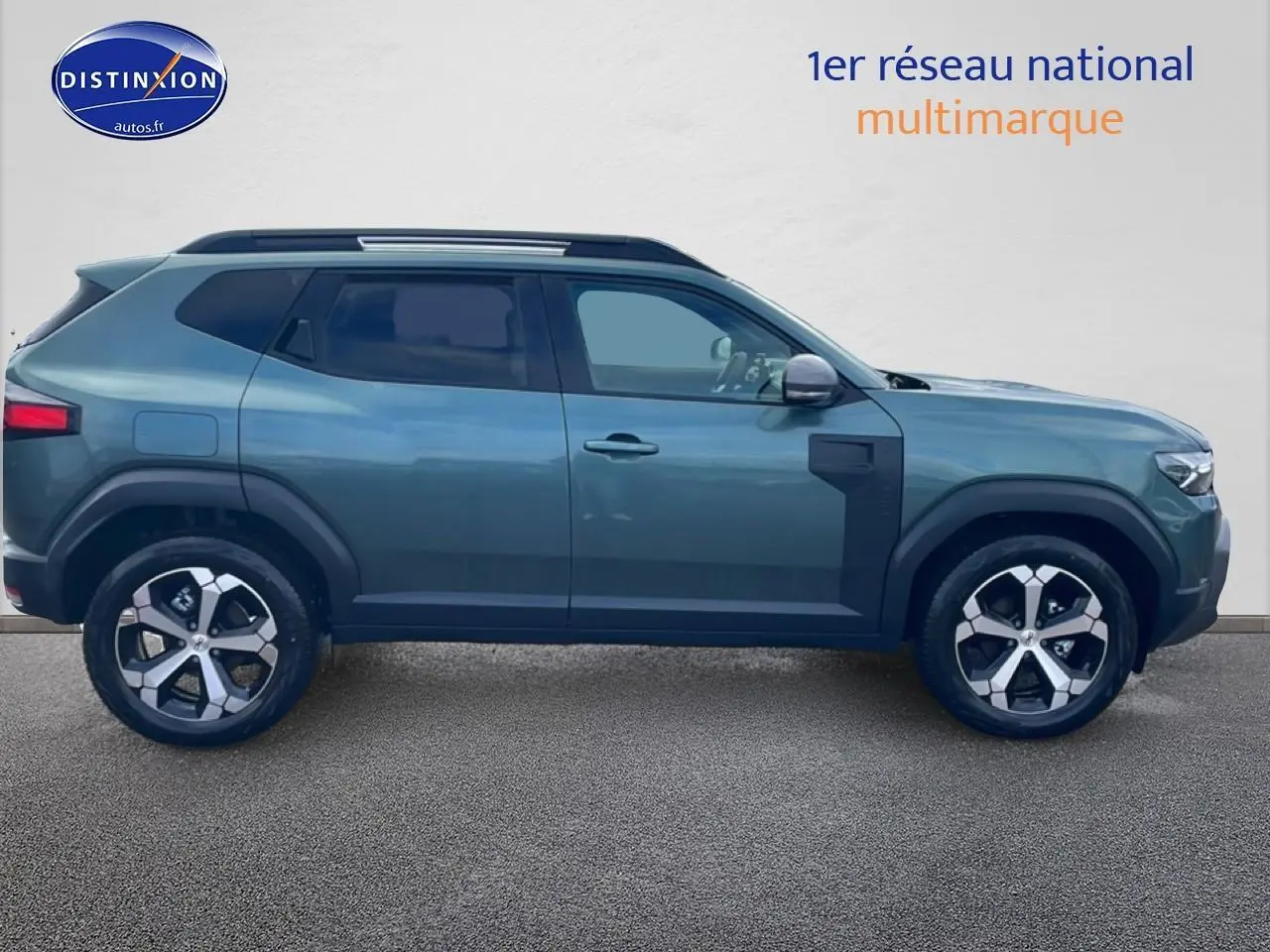 Vue latérale droite d'un Dacia Duster 2026 vert cèdre avec jantes alliage et barres de toit visibles.