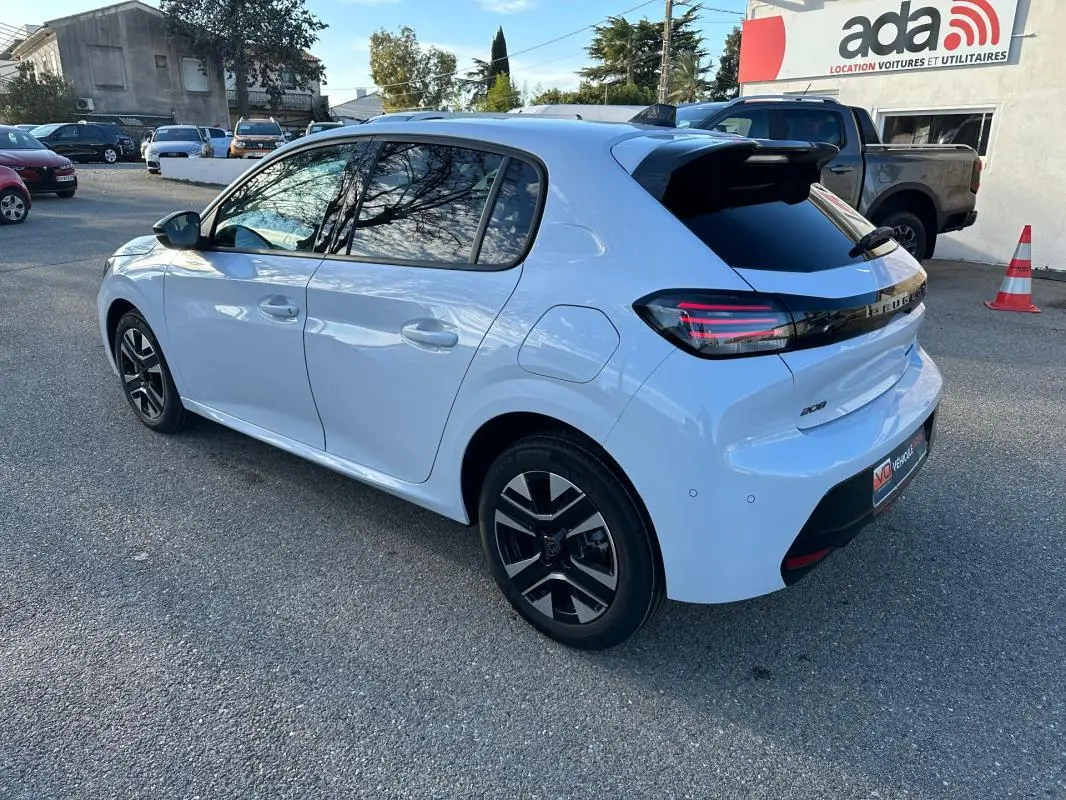 Peugeot 208 Hybrid blanc vue 3/4 arrière droit, jantes alliage noires et feux arrière LED distinctifs.