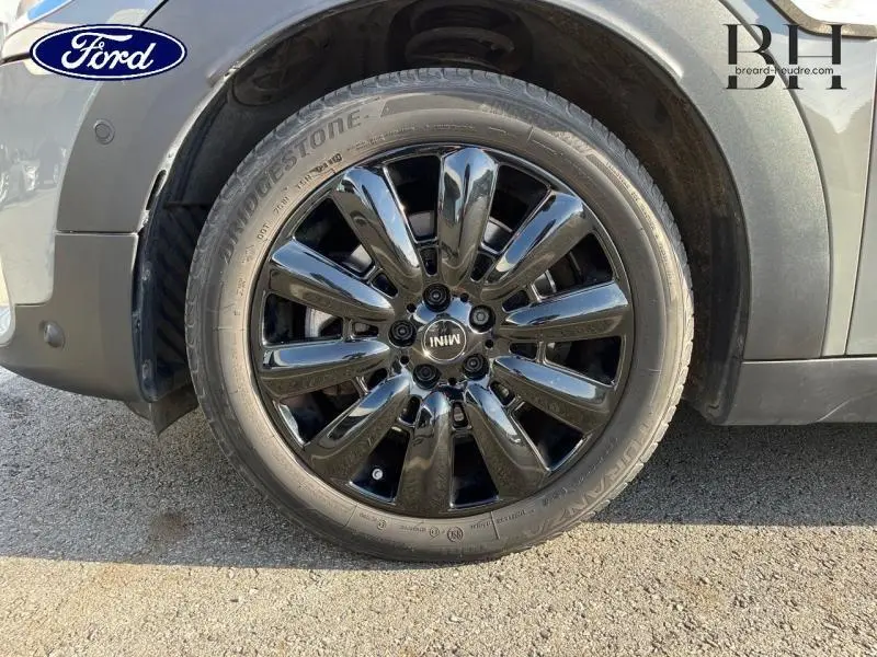 Gros plan sur la roue avant gauche d'une MINI Countryman Moonwalk Grey avec jante alu noire brillante design Black Pin Spoke.