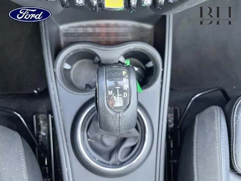 Le levier de vitesse automatique noir de la MINI Countryman Cooper SE vu de dessus avec porte-gobelets et sièges en tissu.