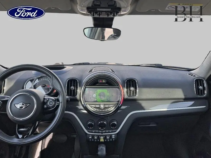 Vue intérieure du tableau de bord de la MINI Countryman Cooper SE en cuir noir avec écran central rond et volant multifonction.