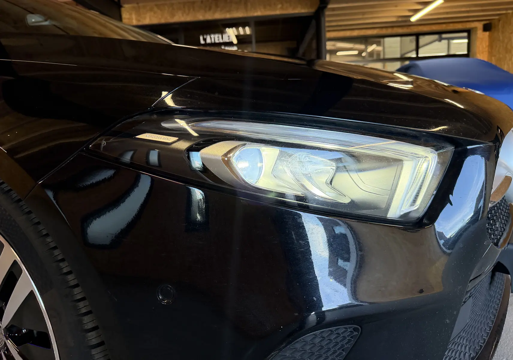 Gros plan sur le phare avant droit noir brillant d'une Mercedes Classe A 2022 avec jante alu visible.