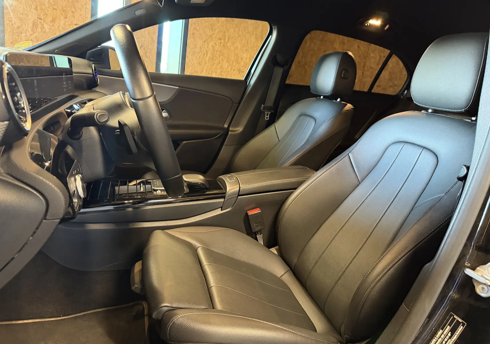 Vue intérieure côté conducteur de la Mercedes Classe A 2022, sièges en cuir noir et tableau de bord moderne avec écran tactile.