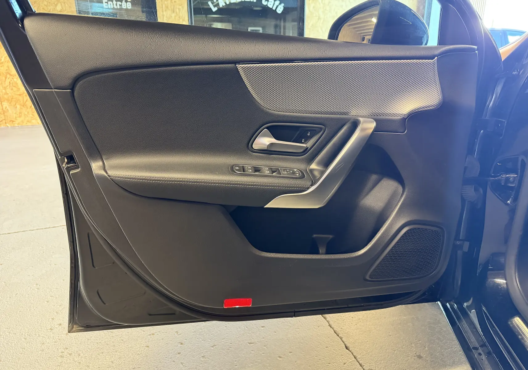 Vue intérieure de la porte avant gauche noire d'une Mercedes Classe A 2022 avec commandes électriques et insert décoratif gris.