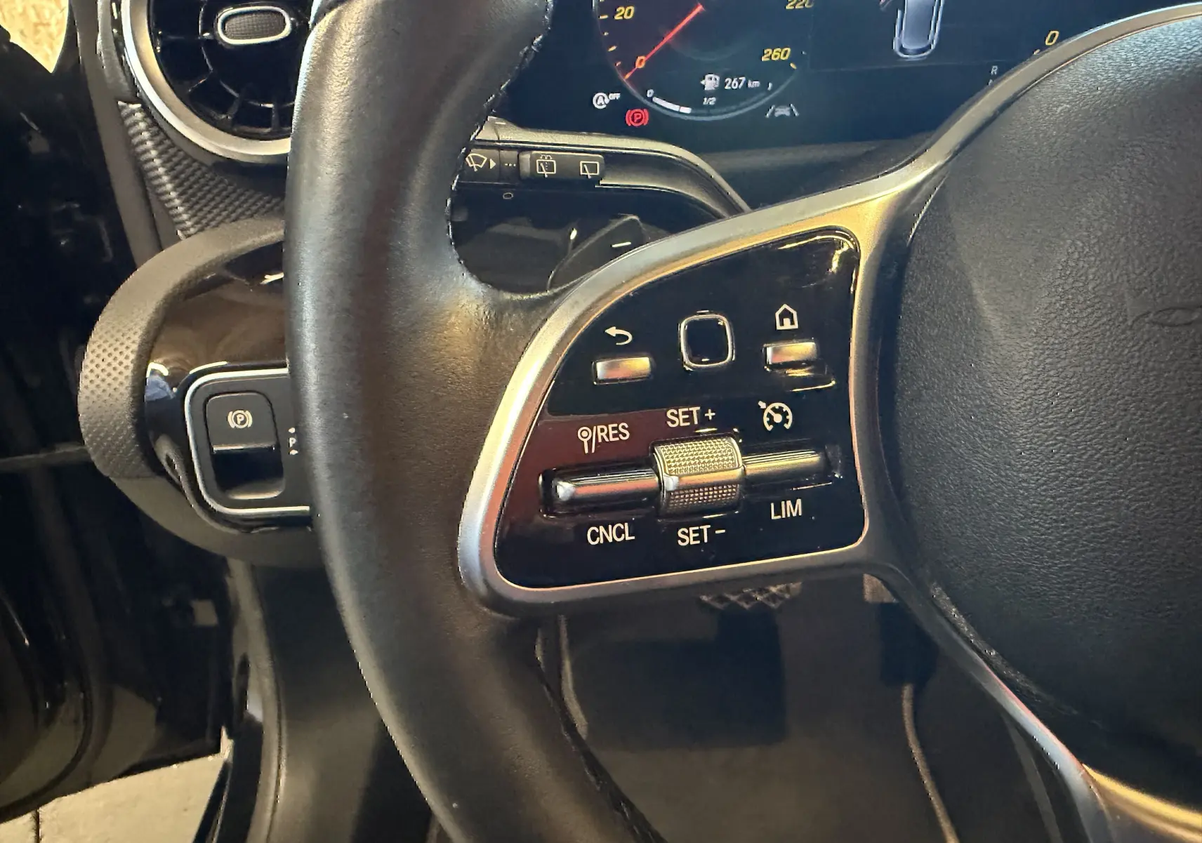 Gros plan sur le volant cuir noir multifonctions côté gauche de la Mercedes Classe A 2022 avec commandes de régulateur de vitesse.