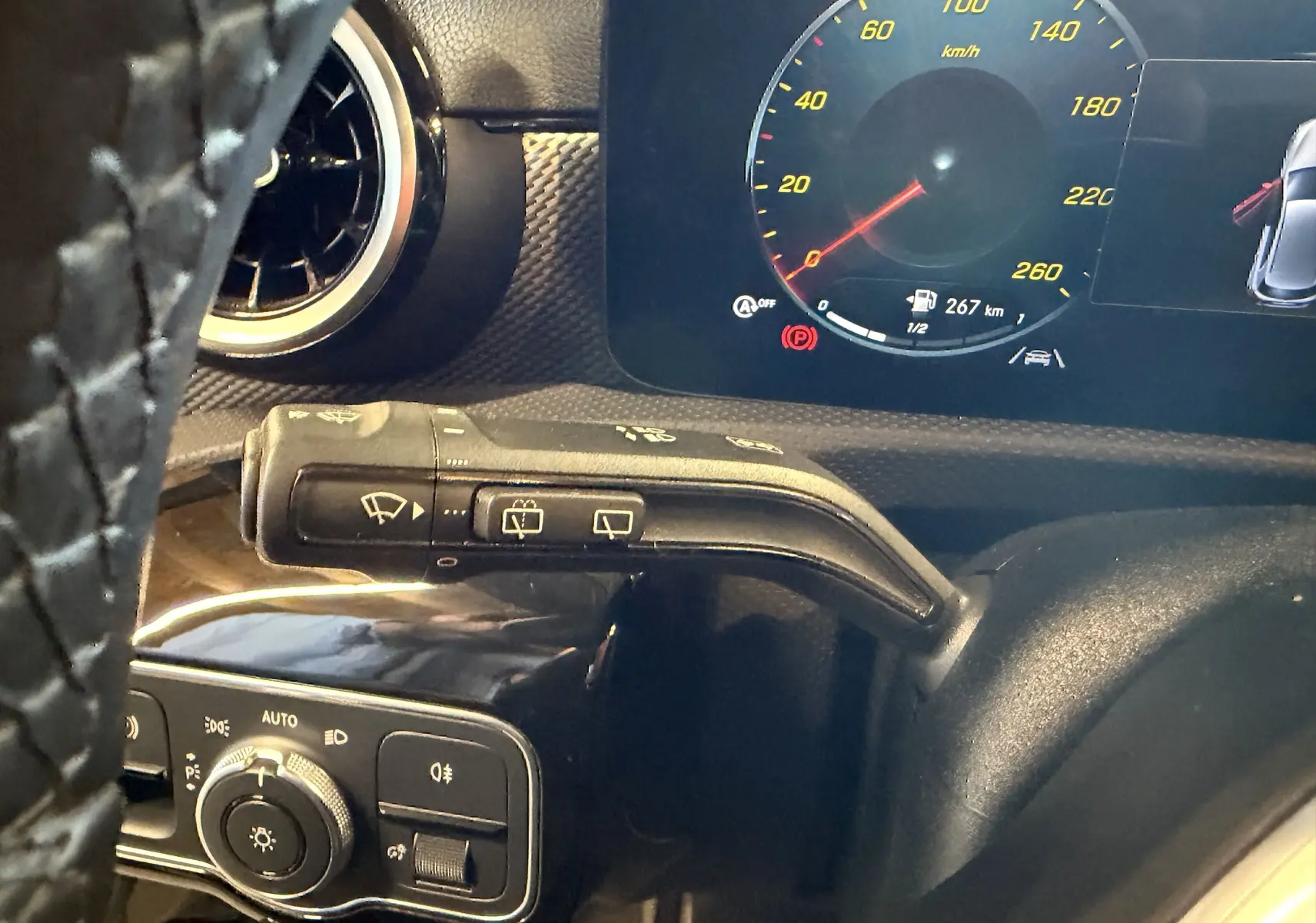 Gros plan sur la commande d’essuie-glace et le tableau de bord numérique d’une Mercedes Classe A noire, intérieur moderne.