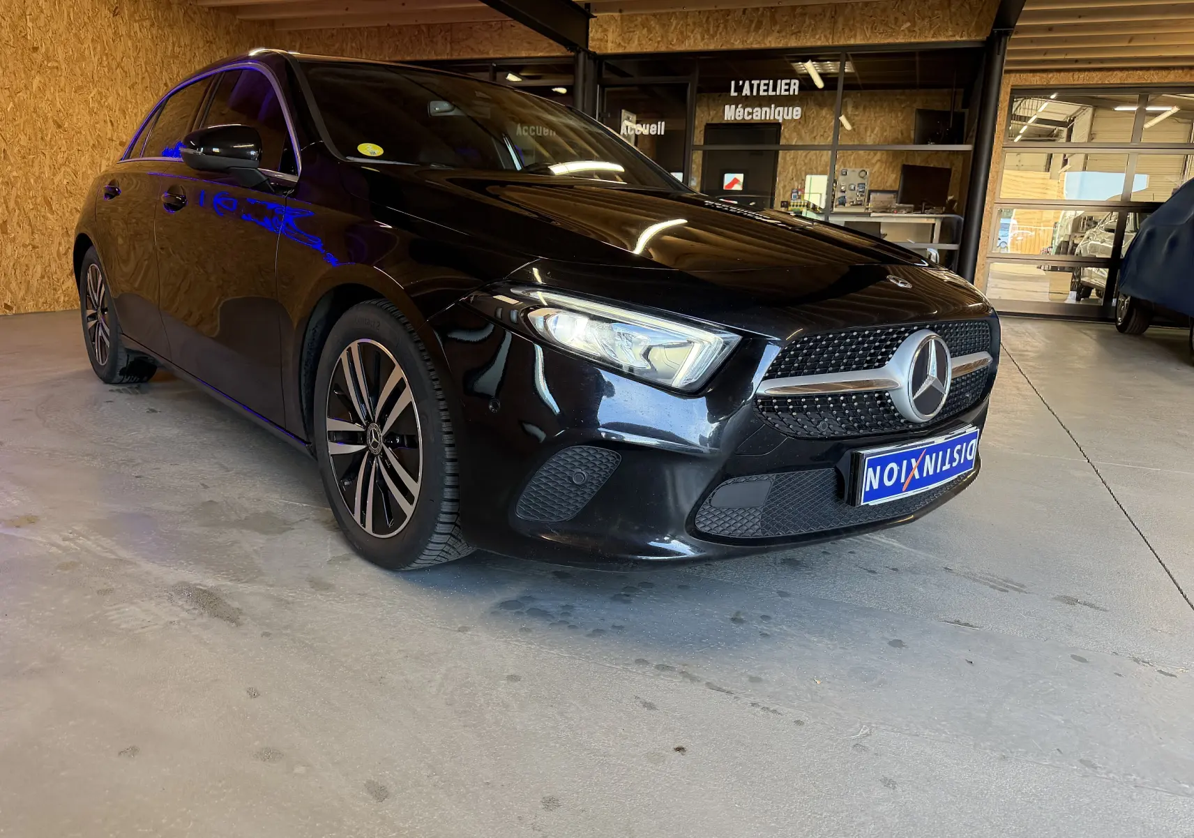 Mercedes Classe A noire vue en 3/4 avant droit dans un garage avec jantes alliage et calandre étoile chromée.