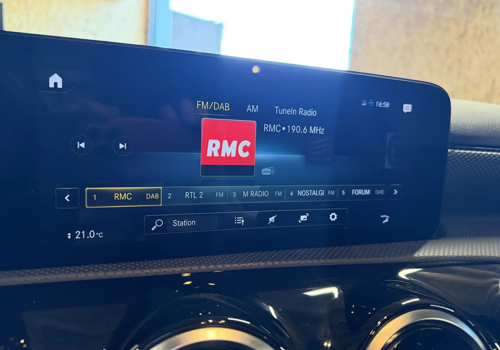Gros plan sur l'écran tactile intérieur de la Mercedes Classe A 2022 affichant la radio RMC, avec tableau de bord noir brillant.